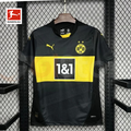 Borussia Dortmund black short-sleeve jersey with a yellow chest band, 1&1 sponsor, yellow BVB crest and Puma logo, alongside a Bundesliga logo graphic.

