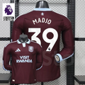 Front and back views of a claret Aston Villa long-sleeve jersey with a light blue collar, white Madjo number 39 print and Visit Rwanda sponsor, alongside Premier League graphics.