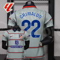 Front and back views of a light grey Atlético Madrid short-sleeve jersey with red horizontal stripes, blue Grimaldo number 22 print and Riyadh Air sponsor, alongside a LaLiga graphic.