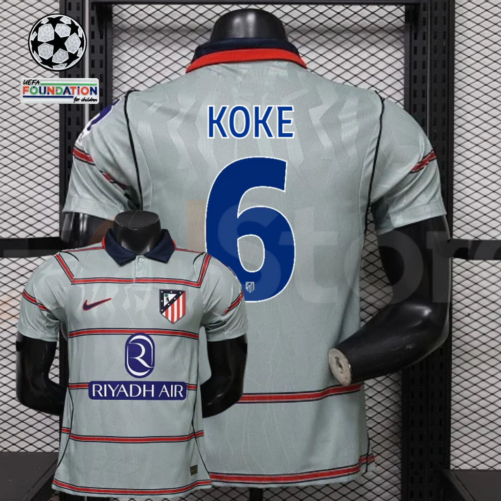  Front and back views of a light grey Atlético Madrid short-sleeve jersey with red horizontal stripes, blue Koke number 6 print and Riyadh Air sponsor, alongside UCL graphics.
