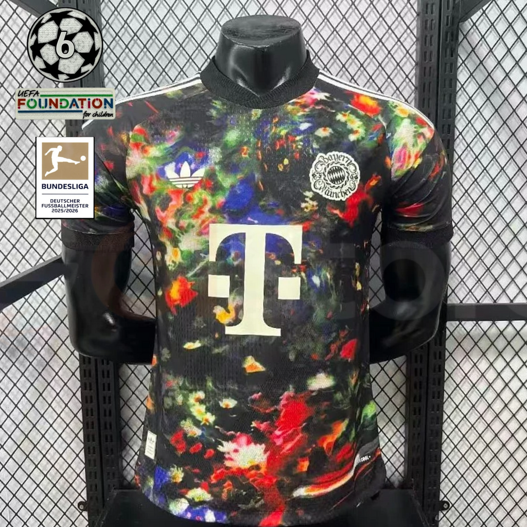 Front view of a black Bayern Munich short-sleeve jersey with a multicolored abstract print, cream club crest, adidas Trefoil and Telekom sponsor, alongside UCL and Bundesliga graphics.