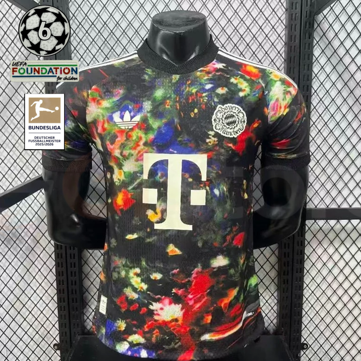 Front view of a black Bayern Munich short-sleeve jersey with a multicolored abstract print, cream club crest, adidas Trefoil and Telekom sponsor, alongside UCL and Bundesliga graphics.