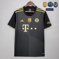 Front view of a black Bayern Munich short-sleeve away jersey with gold shoulder stripes, dotted diagonal patterns, gold club crest and sponsor logo, and a gold FIFA badge.