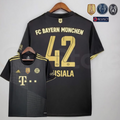 Front and back views of a black Bayern Munich short-sleeve away jersey with gold details, dotted diagonal front patterns and Musiala 42 printing on the back.