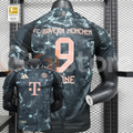 Bayern Munich 2024–2025 short-sleeve away jersey, front and back views, with a dark grey pattern, black panels and copper-coloured KANE number 9 printing.