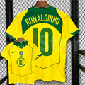 Front and back views of a yellow Brazil retro short-sleeve home jersey with green trim, yellow Ronaldinho lettering on a green upper back panel and green number 10 print.