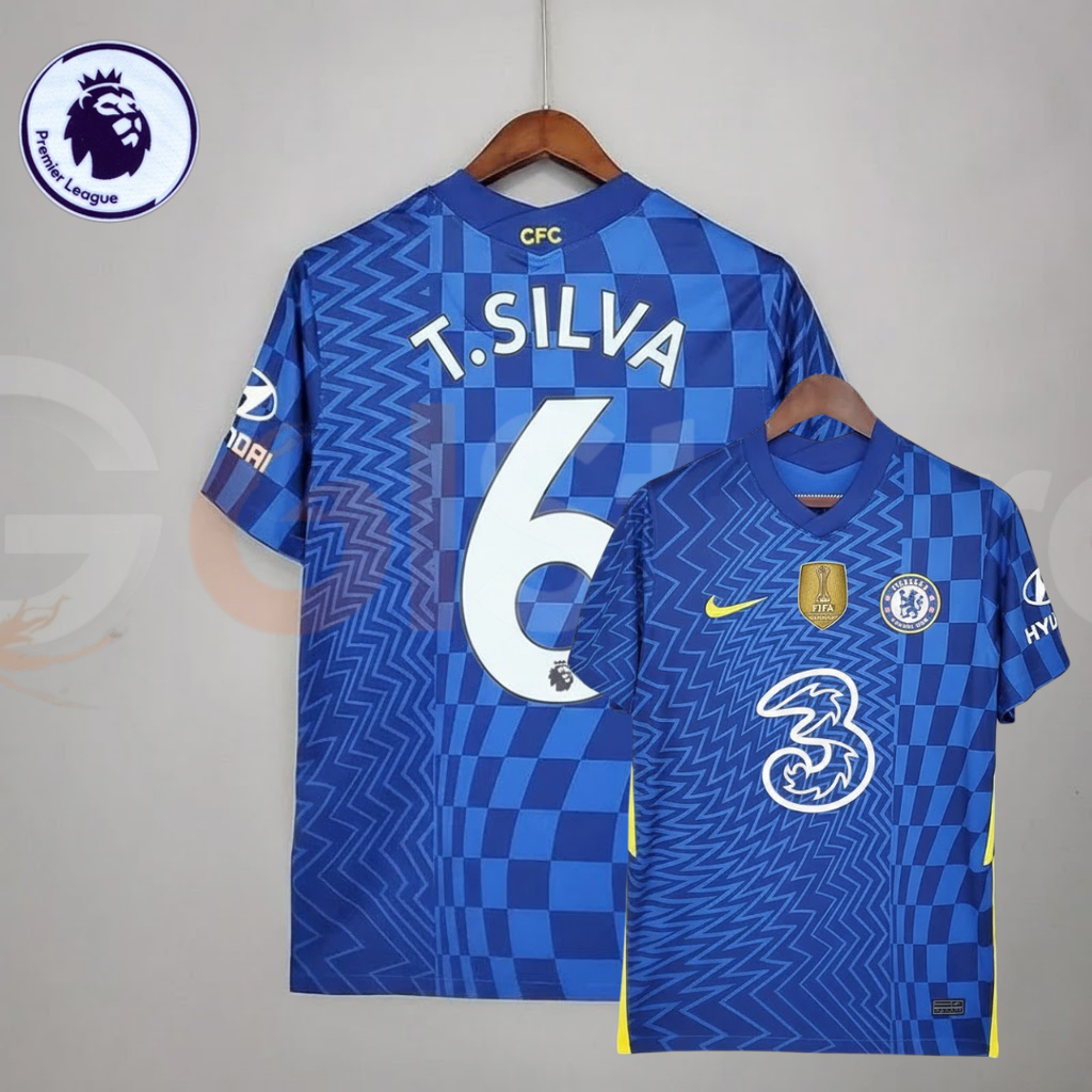 Front and back views of a blue Chelsea FC 2021–2022 short-sleeve home jersey with white T. Silva #6 printing, zigzag and checkerboard patterns, yellow accents and a gold FIFA chest badge.