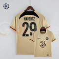 Front and back views of a pale gold Chelsea FC 2022–2023 short-sleeve third jersey with black Havertz #29 printing, a black upper back panel and black and orange sleeve trim.