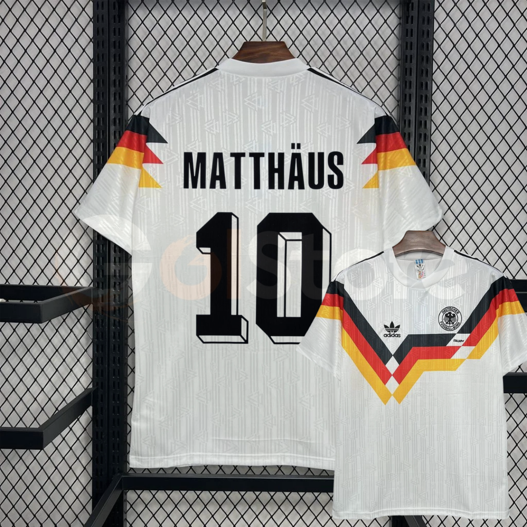  Front and back views of a white Germany 1990 retro short-sleeve home jersey with black, red and gold stripes and black Matthäus number 10 print.