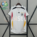 Front view of a white Germany 2006 retro short-sleeve home jersey with black shoulder details, red and gold side panels, and the German football crest.