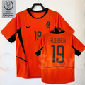 Netherlands orange short-sleeve retro jersey, front and back views with Robben 19 print, black collar and side panels, alongside a 2002 World Cup graphic.
