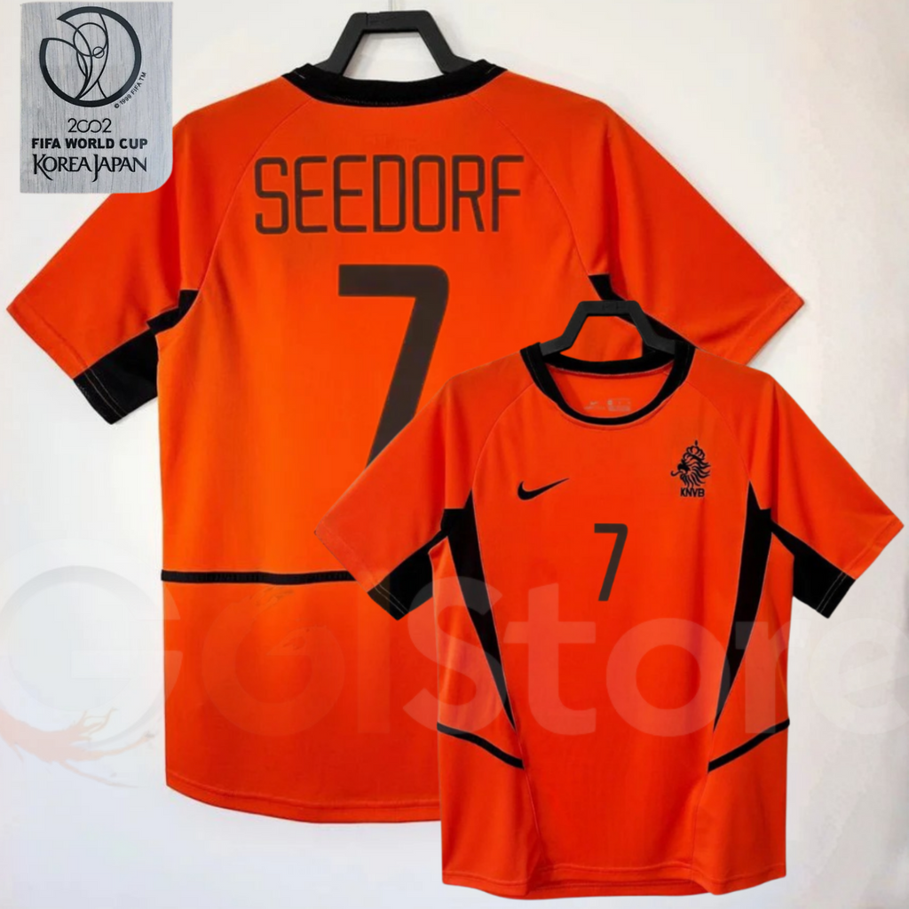 Netherlands orange short-sleeve retro jersey, front and back views with SEEDORF 7 print, black collar and side panels, alongside a 2002 World Cup graphic.

