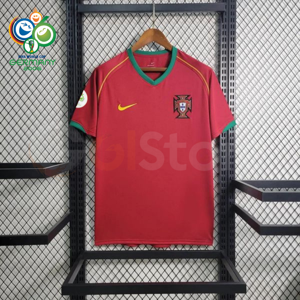 Front view of a Portugal 2006 retro red short-sleeve home jersey with green collar and sleeve trim, gold detailing, national team crest and a World Cup sleeve patch.