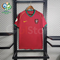 Front view of a Portugal 2006 retro red short-sleeve home jersey with green collar and sleeve trim, gold detailing, national team crest and a World Cup sleeve patch.