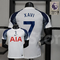 Front and back views of a white Tottenham Hotspur short-sleeve home jersey with navy and grey sleeves, navy Xavi number 7 print and red AIA sponsor.